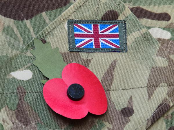 Close up of a British army uniform, a poppy and a UK flag patch