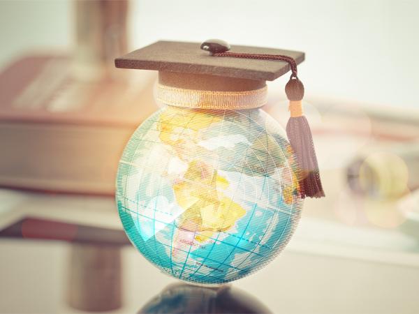 a little world globe wearing a tiny graduation cap.