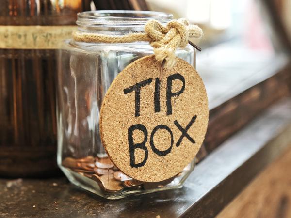 a glass jar with a label reading 'TIP BOX' sat on a counter top