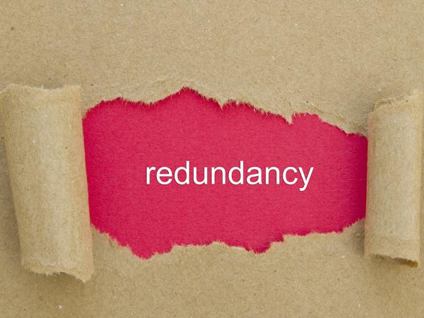 a sheet of brown paper ripped in the middle to reveal red paper with the word 'REDUNDANCY' in white ink. 