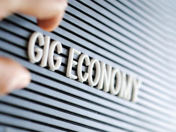 the words 'GIG ECONOMY' spelt out in white letters on a dark coloured board. 