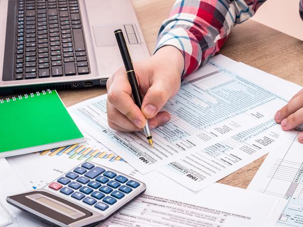 a person sat at a desk surrounded by various stationary, filling out a form.