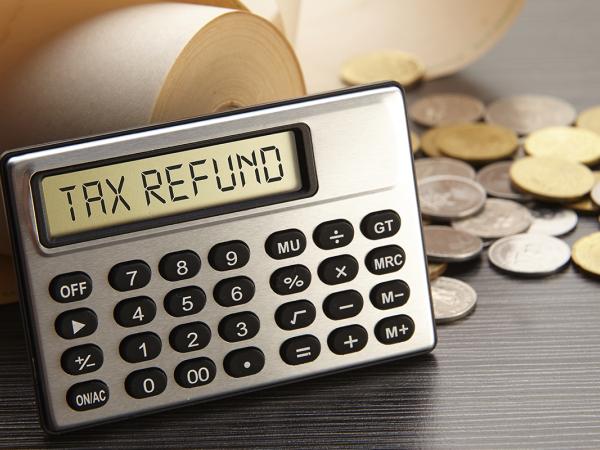 a calculator displaying the words 'TAX REFUND' coins scattered in the background