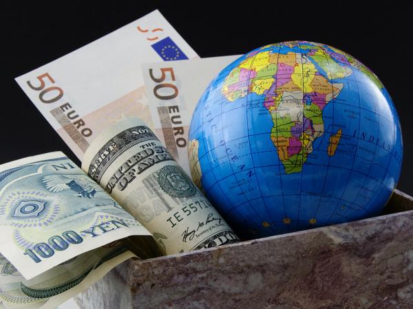 a globe of the world sat in a box with various foreign currency