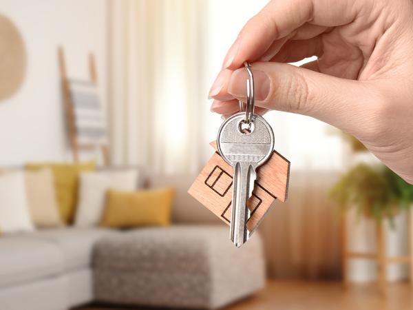 a person holding up a set of keys, the background shows a living room