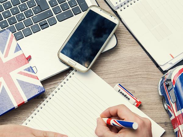 a person at a desk with a laptop, phone, notebook and various stationary with the UK flag on it