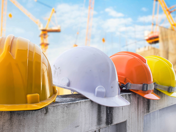 Various contractor hard hats sat on top of a wall. 