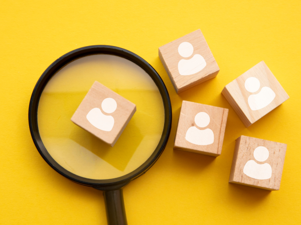 5 wooden blocks, one is being looked at through a magnifying glass. 