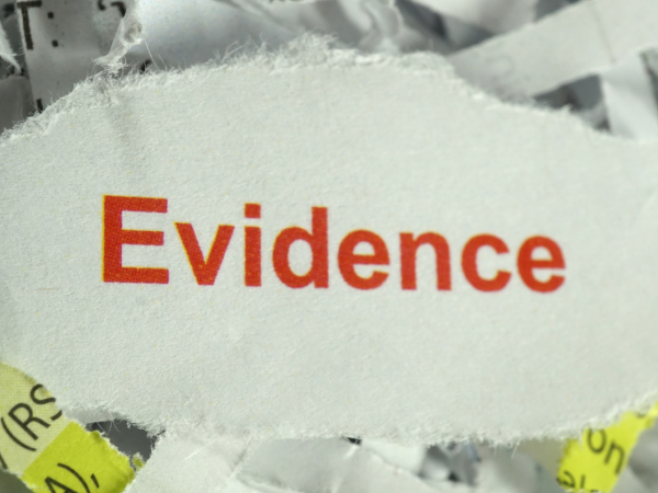 a bag of shredded paper, with a larger torn piece of paper containing the word 'EVIDENCE' in red text. 