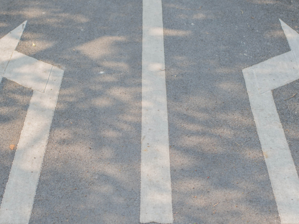 A road with lines and arrows one pointing left and one pointing right. 