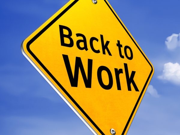 Yellow traffic sign with the words 'BACK TO WORK' in black text against a background of the blue sky. 