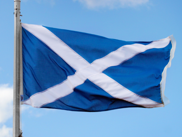 A blue sky with a Scottish flag blowing in the breeze. 