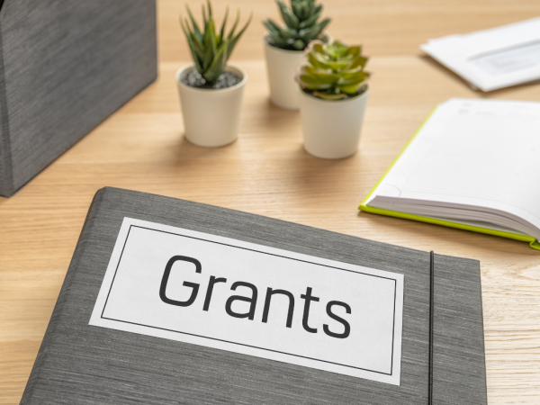 A desk with a folder titled 'GRANTS'. 