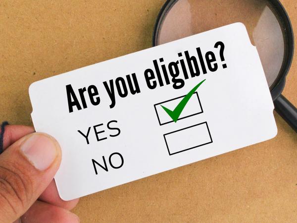 A piece of white card showing the words 'ARE YOU ELIGIBLE?' with tick boxes beneath for 'YES' and 'NO' the tickbox beside the word 'YES' is ticked. 
