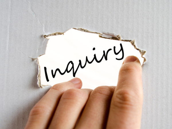 a sheet of cardboard with a hole in the centre, through the hole the word 'INQUIRY' can be seen. 