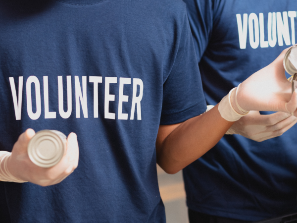 A number of people in blue t-shirts with the word 'VOLUNTEER' in white text on the front.