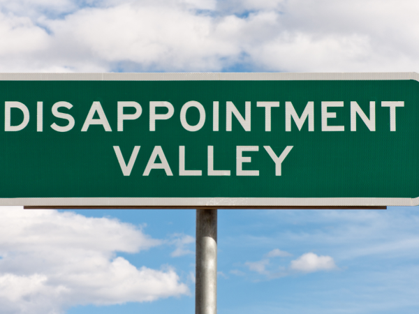 A green road sign with the words 'DISAPPOINTMENT VALLEY' in white text.