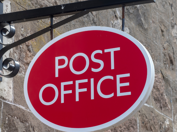 The 'POST OFFICE' logo on a sign outside a building.