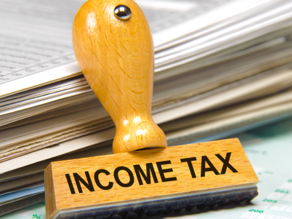 Documents and papers next to a hand stamper that reads 'INCOME TAX'. 