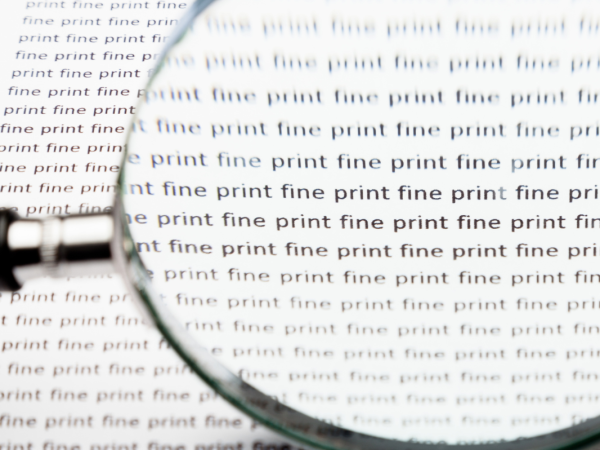 A page of text repeating the words 'FINE PRINT' in black text with a magnifying glass looking over it.
