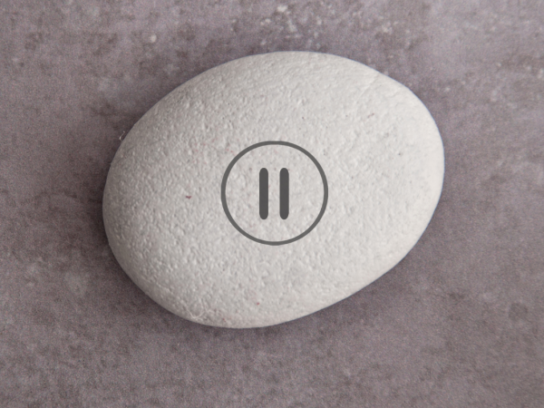 A stone with a pause button stamped onto it.