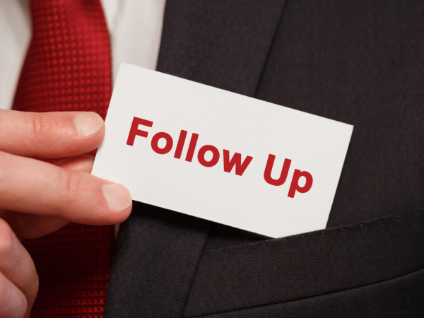 A person pulling a small card from their pocket, the card reads 'FOLLOW UP' in red text.