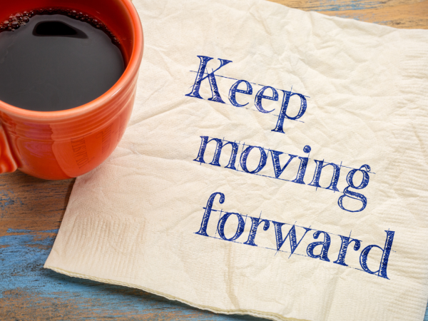 a napkin with the words 'KEEP MOVING FORWARD' next to a coffee cup.