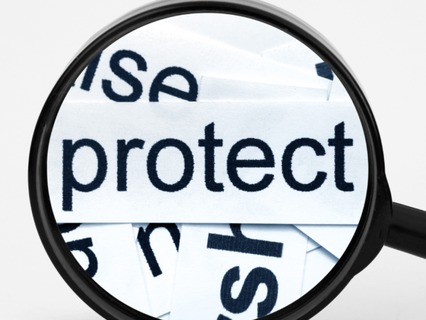 A magnifying glass hovering over the word 'PROTECT'