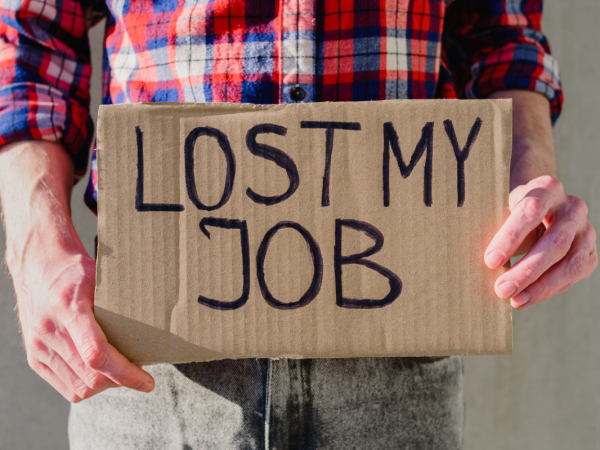 A person holding a piece of cardboard with the words 'LOST MY JOB' written on it in black ink