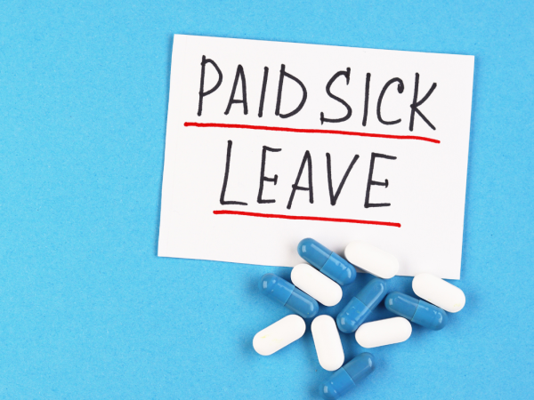 A bunch of blue and white pills and a sign saying 'PAID SICK LEAVE' 