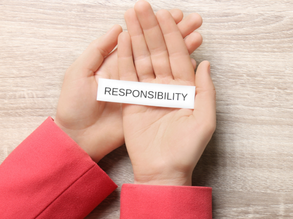 A person holding a small piece of white paper with the word 'RESPONSIBILITY' on it in black text.