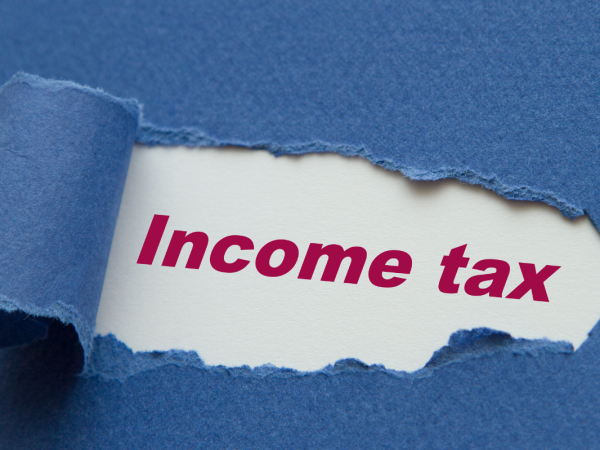 A blue sheet of paper with a tear in the middle, through the tear the words 'INCOME TAX' can be seen in red text. 