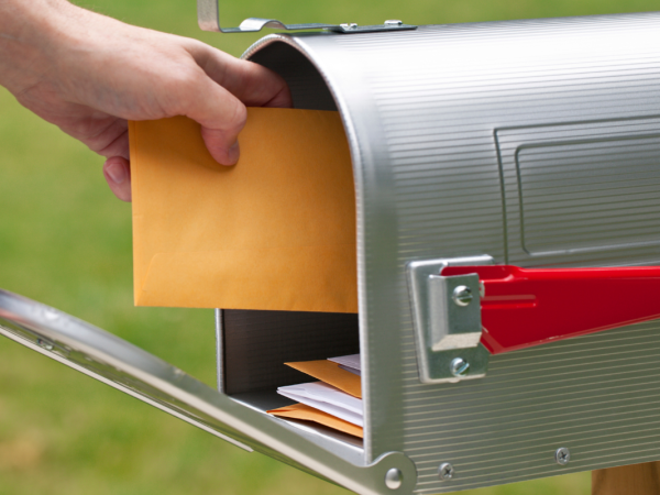 A person receiving a brown envelope in the postbox 