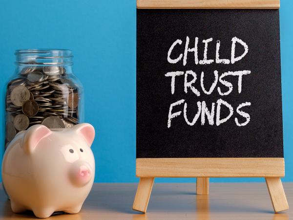 Image of a piggy bank and a board with the words child trust funds written on it