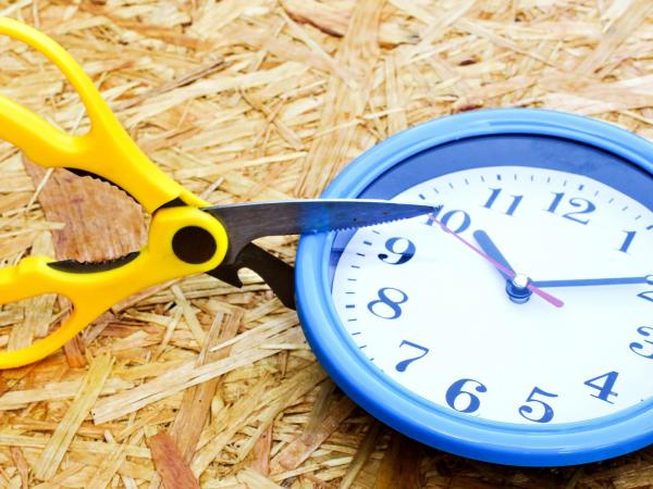 scissors cutting into a clock to signal cut in working hours