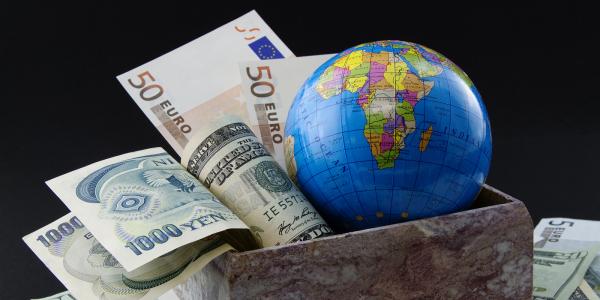 a globe of the world sat in a box with various foreign currency
