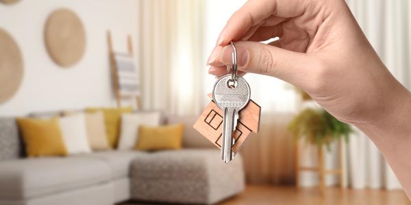 a person holding up a set of keys, the background shows a living room