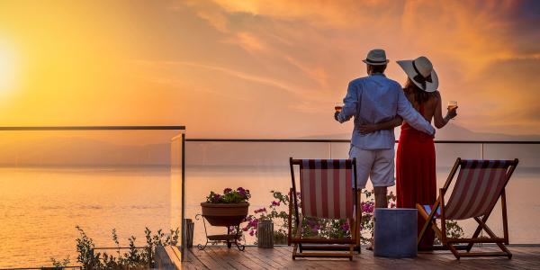 a couple looking out over a balcony at a sunset