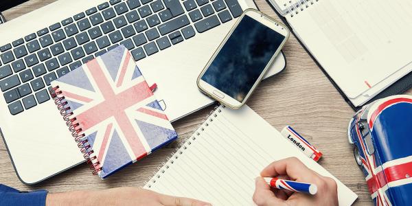a person at a desk with a laptop, phone, notebook and various stationary with the UK flag on it