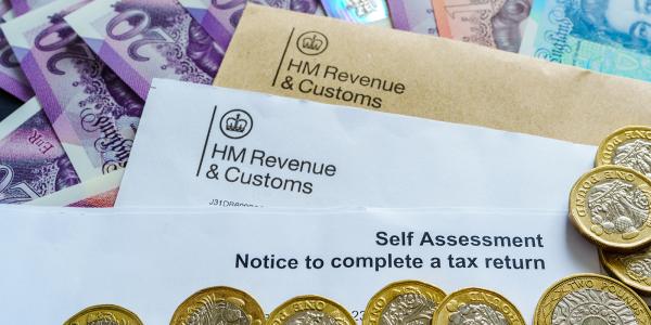 A letter from HMRC with the words 'SELF ASSESSMENT NOTICE TO COMPLETE A TAX RETURN' on the top, surrounded by British currency