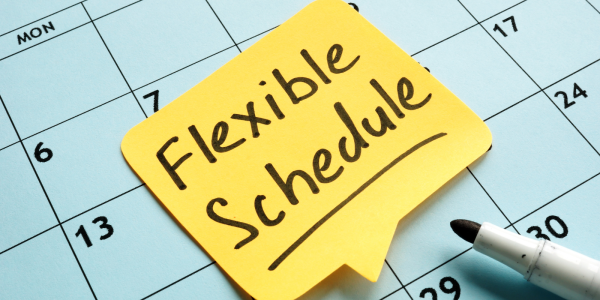 A calendar with a yellow post-it note, the note reads 'FLEXIBLE SCHEDULE' in black ink.