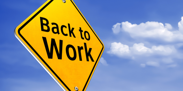 Yellow traffic sign with the words 'BACK TO WORK' in black text against a background of the blue sky. 