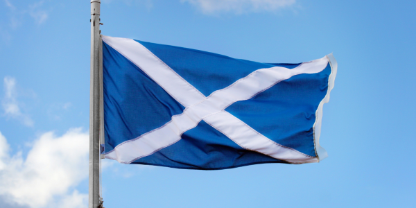 A blue sky with a Scottish flag blowing in the breeze. 