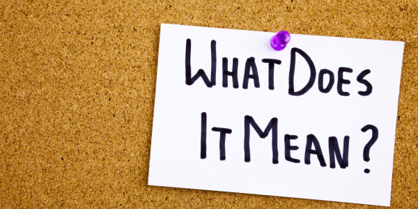 A pin board with a paper attached by a purple pin, the paper reads 'WHAT DOES IT MEAN?'. 