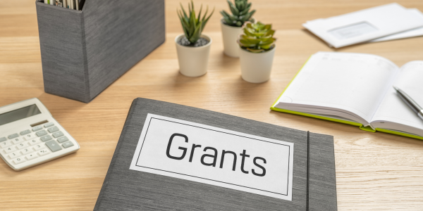 A desk with a folder titled 'GRANTS'. 