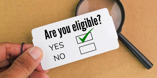 A piece of white card showing the words 'ARE YOU ELIGIBLE?' with tick boxes beneath for 'YES' and 'NO' the tickbox beside the word 'YES' is ticked. 