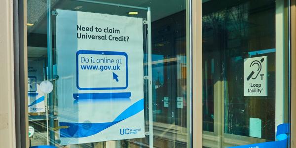 A window with a poster showing that says 'NEED TO CLAIM UNIVERSAL CREDIT?' 