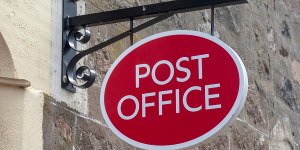 The 'POST OFFICE' logo on a sign outside a building.