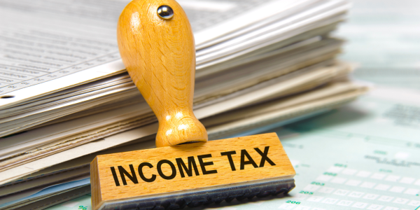 Documents and papers next to a hand stamper that reads 'INCOME TAX'. 