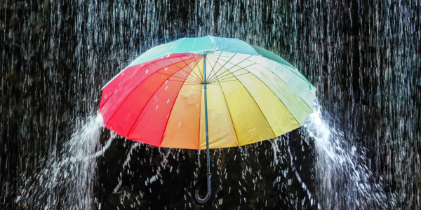 A colourful umbrella with a downpour of water